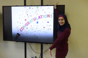 Hala standing next to Congratulations display in the lab