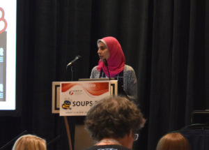 Close-up of Hala Assal on stage, presenting her work at SOUPS 2018