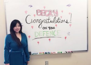 Becky Jeong standing in the lab next to the whiteboard after her Masters thesis defence