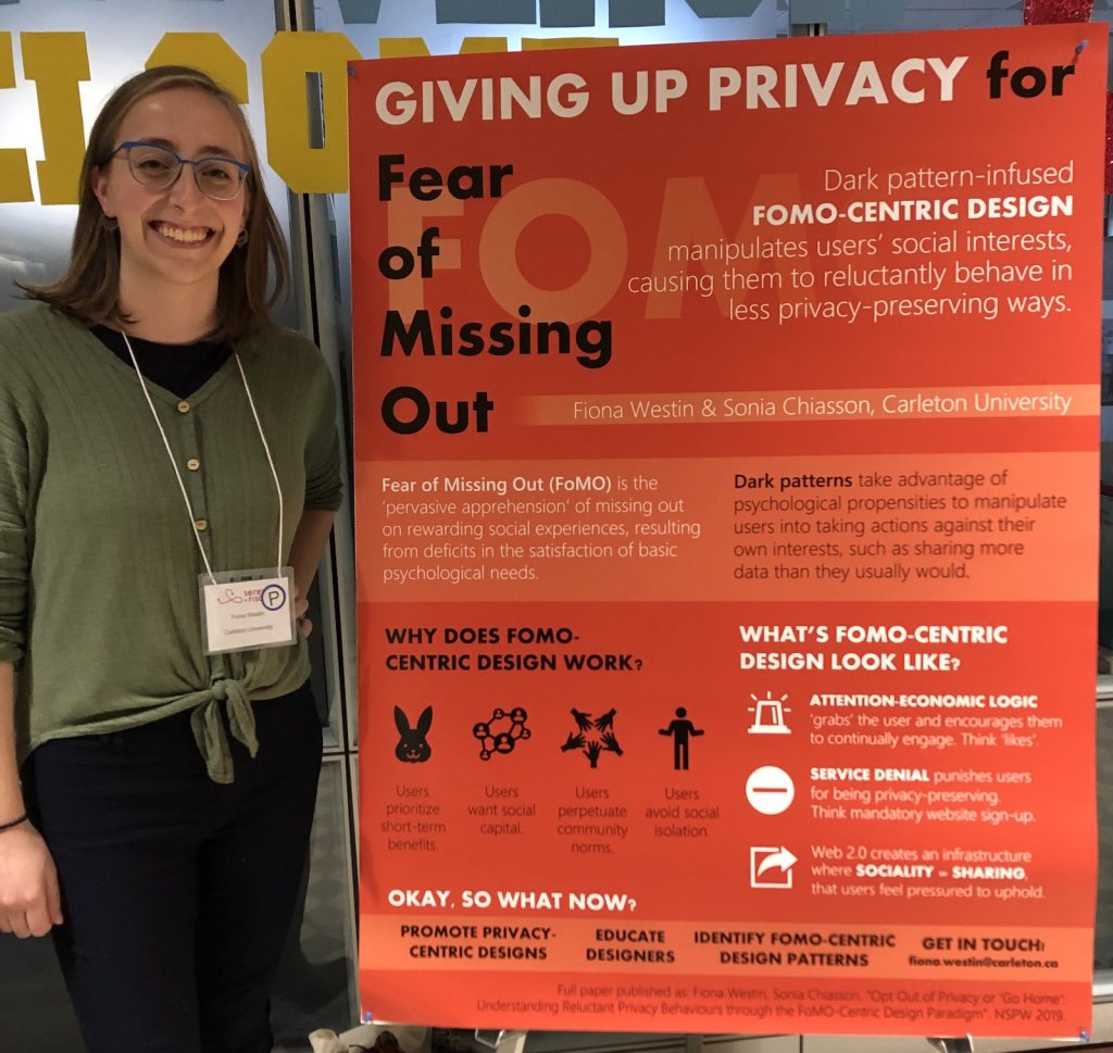 Fiona stands next to her poster on Giving up privacy for Fear of Missing Out at the 2019 SERENE-RISC conference