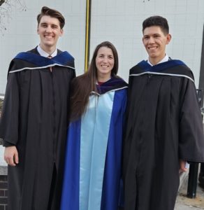 Max, Sonia, and Sebastian standing outside together in graduation robes