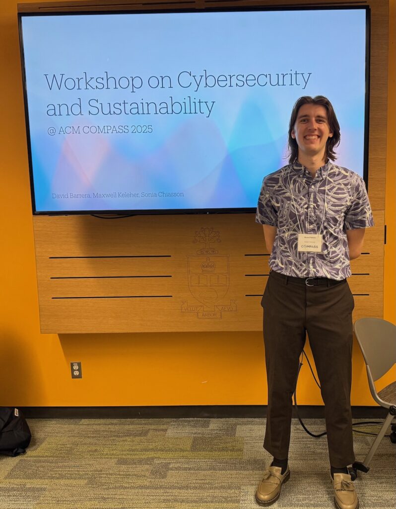 Max standing in front of a screen announcing the Workshop on Cybersecurity and Sustainability at COMPASS 2025